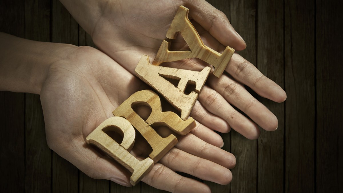 Man holding pray word in palm with wooden background