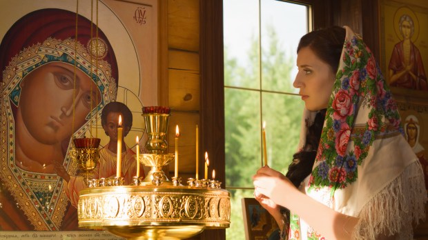 Russian woman with candles in Orthodox Russian Church