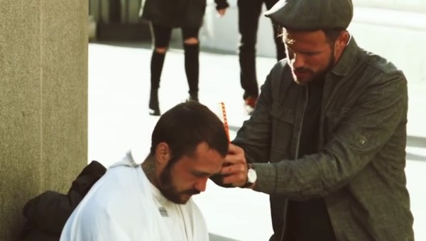 Mężczyzna obcina włosy bezdomnemu na ulicy