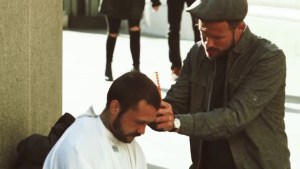 Mężczyzna obcina włosy bezdomnemu na ulicy