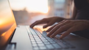 Woman working at home office hand on keyboard close up