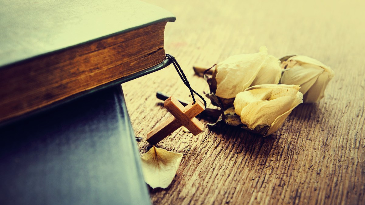 The Holy Bible and a crucifix on the wooden table.