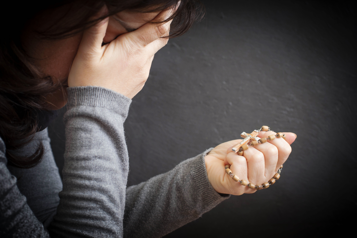 Woman praying with rosary in her hand