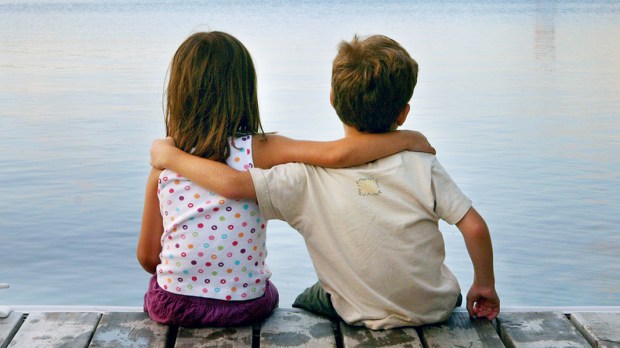 Chłopiec i dziewczynka siedzą nad jeziorem