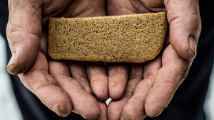 Biedny człowiek trzyma w dłoniach kawałek chleba