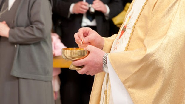 Ksiądz trzymający Komunię Świętą w dłoniach