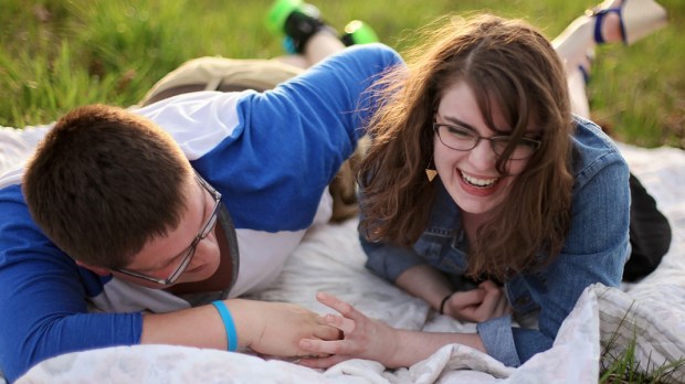 Para leży na kocu na trawie