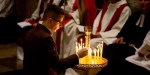 Mężczyzna zapala świeczkę w czasie liturgii