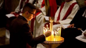 Mężczyzna zapala świeczkę w czasie liturgii