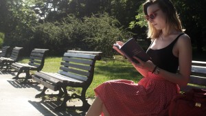 Kobieta na ławce w parku czyta książkę
