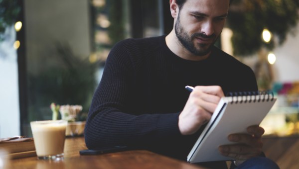 Mężczyzna zapisuje coś w notatniku w kawiarni