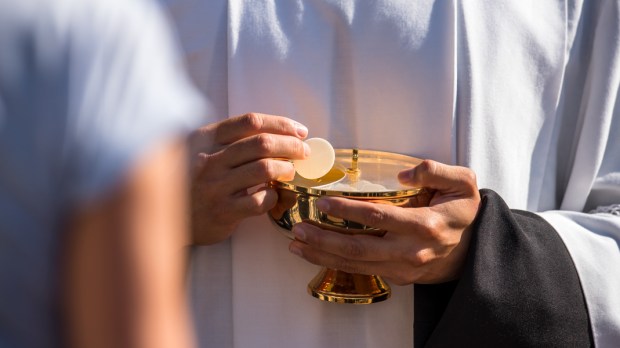 Catholic priest giving beliver a Holy Communion