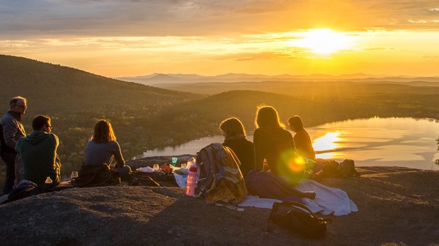 Ludzie oglądają zachód słońca w górach