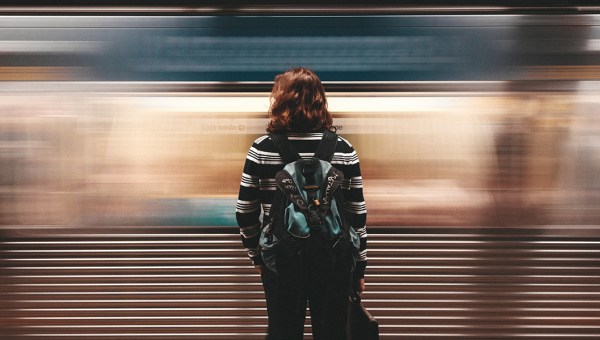 Kobieta stojąca na peronie metra przed przejeżdżającym wagonem