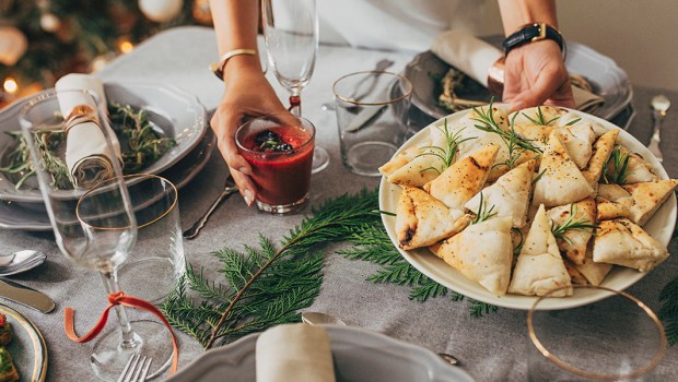 Kobieta stawia talerz z potrawą na udekorowanym wigilijnym stole