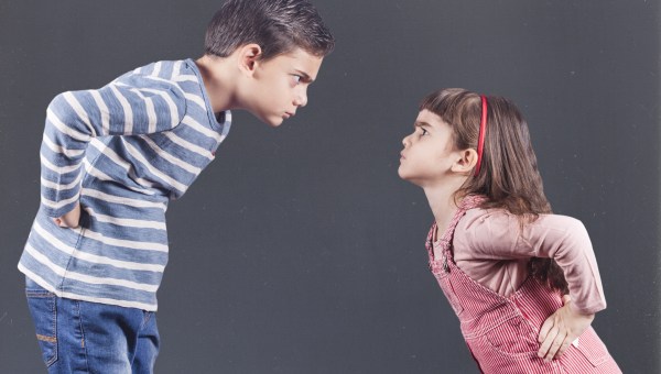 Dwójka dzieci trzymających się pod bokiem i patrzących na siebie wilkiem