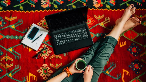 Nogi dziewczyny leżącej na dywanie z laptopem