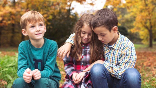 Trójka małych dzieci siedząca razem w parku