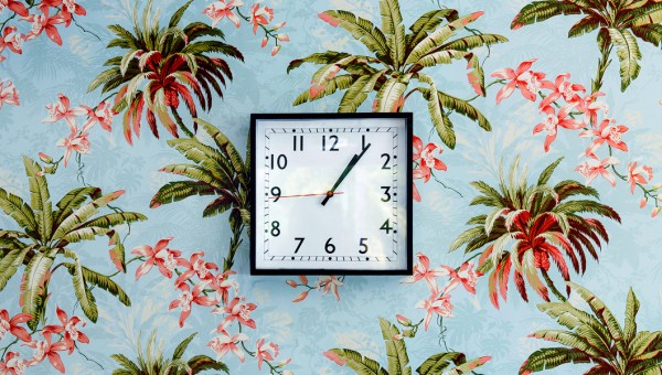 Kwadratowy zegar na ścianie pokrytej dekoracyjną tapetą