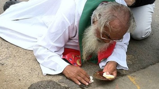 KSIĄDZ PODNOSI EUCHARYSTIĘ Z ZIEMI