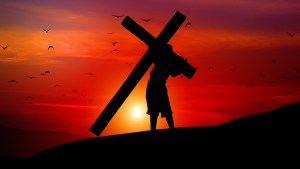 Jezus dźwigający krzyż na tle zachodzącego słońca