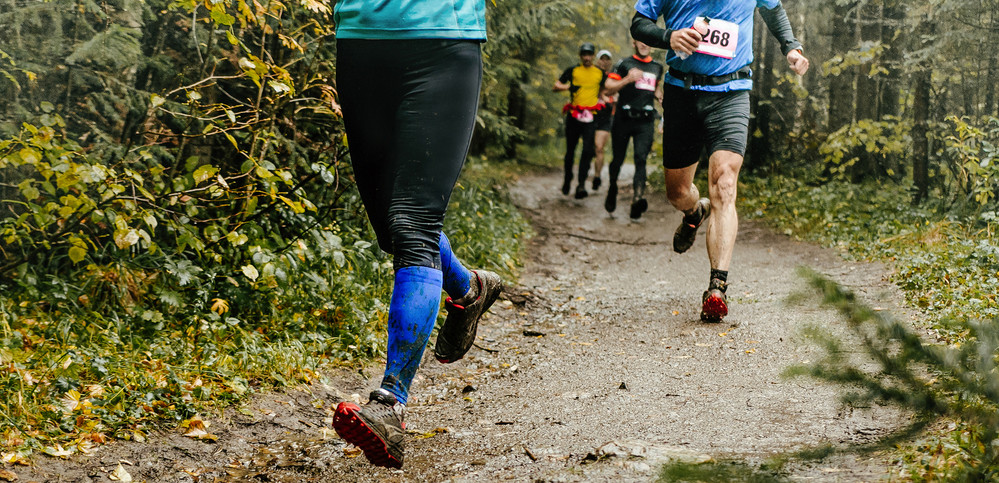 WEB2 &#8211; group runners run forest trail feet in mud &#8211; shutterstock_5791763381.jpg