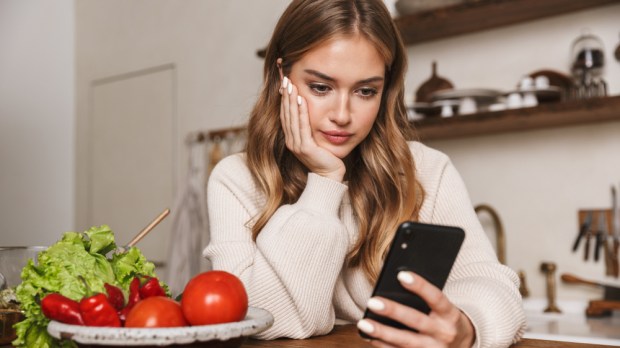 WOMAN LOOKING AT PHONE WHILE COOKING