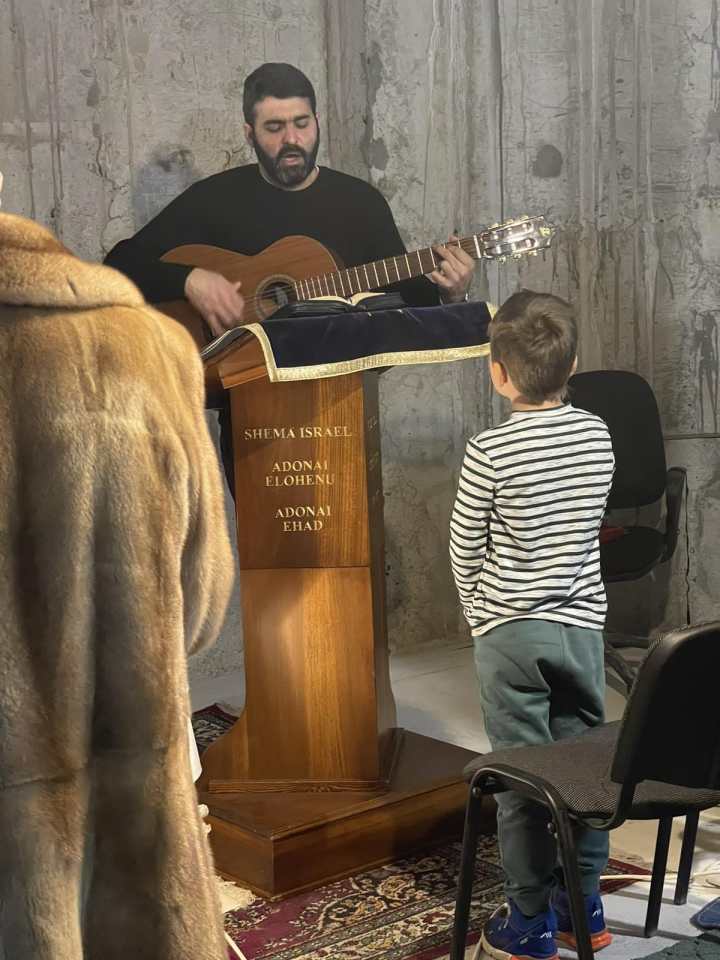 Ojciec Lucas Perozzi gra na gitarze i śpiewa podczas adoracji w czasie wojny. Adoracja odbywa się w schronisku przy parafii św. Antoniego w Kijowie/Kijowie.