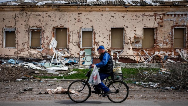 rowerzysta przejeżdża obok budynku zniszczonego przez Rosjan w jednej z wiosek na Ukrainie