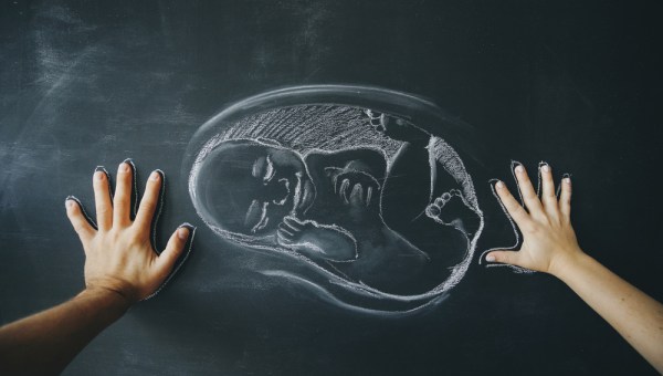 dziecko narysowane kredą na tablicy, dłonie rodziców obok