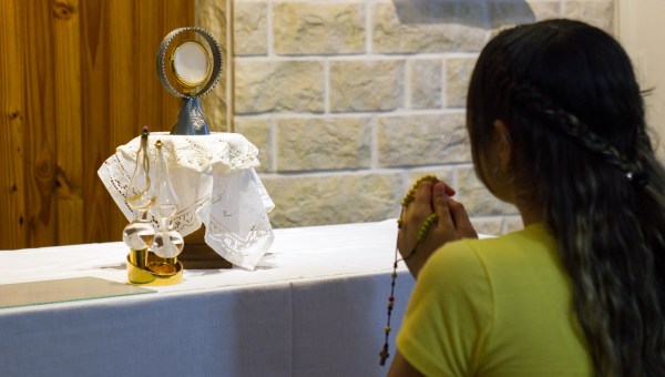 kobieta modli się na różańcu, adorując Pana Jezusa w Najświętszym Sakramencie