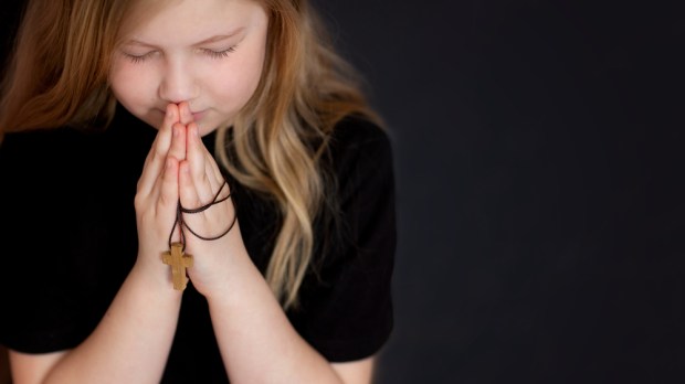 dziewczynka modli się ze złożonymi rękami