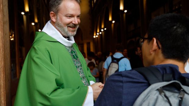 ksiądz wita się z wiernymi przed kościołem