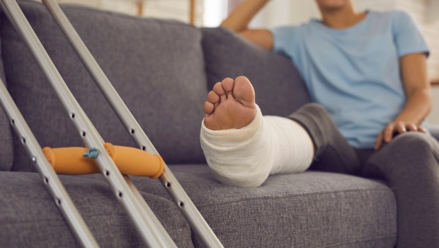 kobieta ze złamaną nogą siedzi na kanapie w salonie