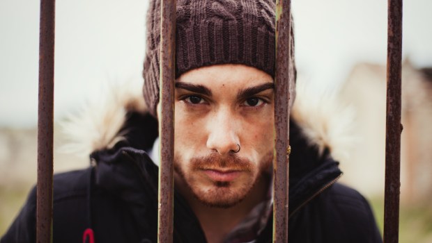 mężczyzna w czapce spogląda zza krat