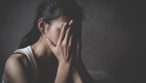 skrzywdzona kobieta skrywa twarz w dłoniach