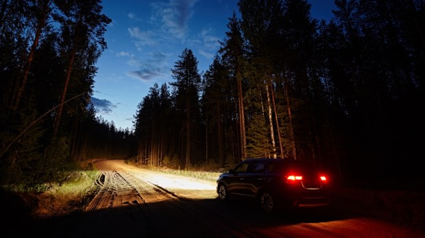 samochód jadący przez las nocą po piaszczystej drodze