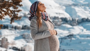 uśmiechnięta kobieta w ciąży stoi w zimie w kurorcie