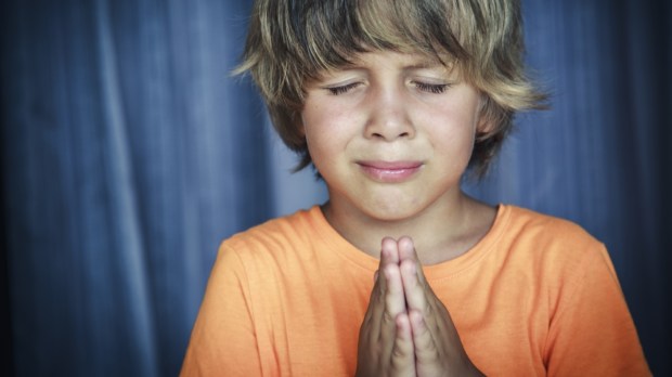 chłopiec modli się gorąco ze złożonymi rękami