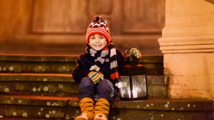 chłopiec siedzi na schodach przed kościołem i trzyma lampion adwentowy
