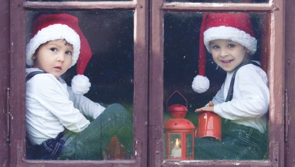 dwaj chłopcy siedzą na parapecie okna i oglądają zimowy krajobraz