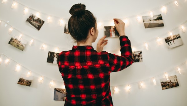kobieta wiesza zdjęcia na ścianie