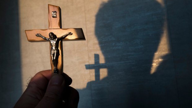 wierzący mężczyzna modli się trzymając w ręku krucyfiks