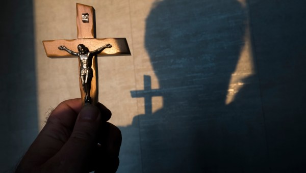 wierzący mężczyzna modli się trzymając w ręku krucyfiks