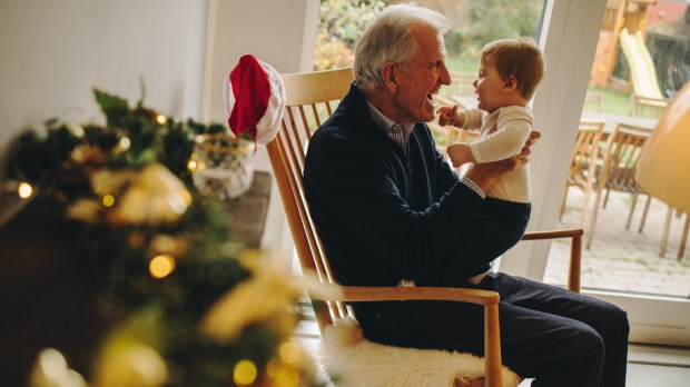 dziadek bawi się z kilkumiesięcznym wnukiem w scenerii bożonarodzeniowej