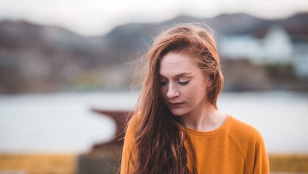 Pensive girl in red hair and an orange sweater