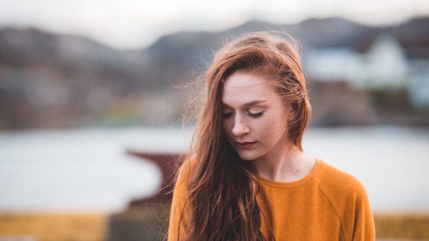 Pensive girl in red hair and an orange sweater