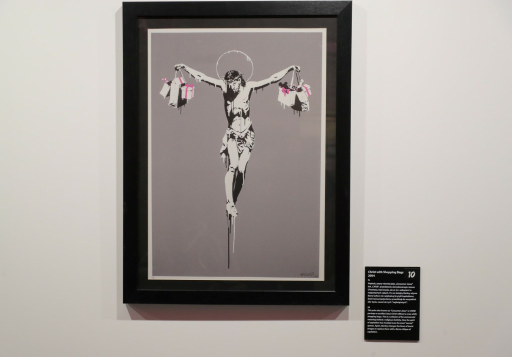 Praca artysty znanego jako Banksy przedstawiająca Chrystusa wiszącego na krzyżu i trzymającego w rękach torby z zakupami