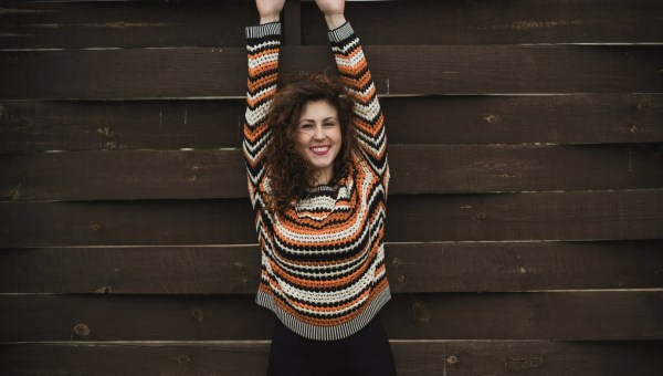 radosna kobieta stoi przy ogrodzeniu i wyciąga ręce w górę