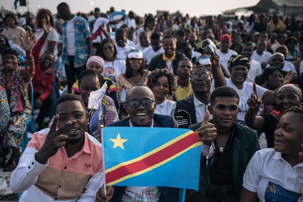 A man holds a Democratic Republic of Congo flag as attendees gather ahead of the arrival of Pope Francis for the mass at the N'Dolo Airport in Kinshasa